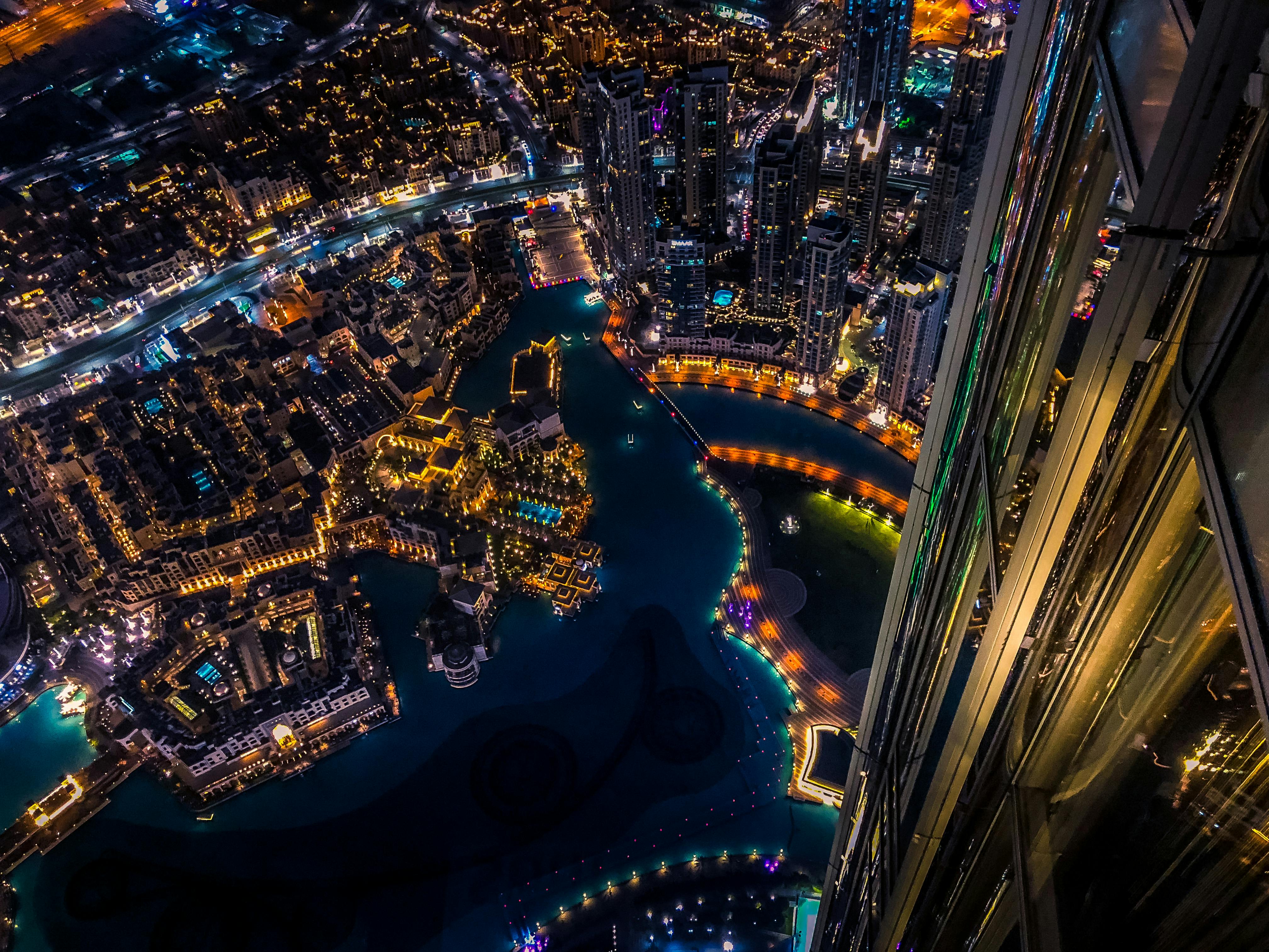 Vibrant aerial cityscape of Dubai at night with illuminated skyscrapers and urban landscape.